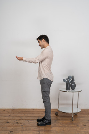 Vue latérale d'un homme en vêtements décontractés debout avec les mains tendues