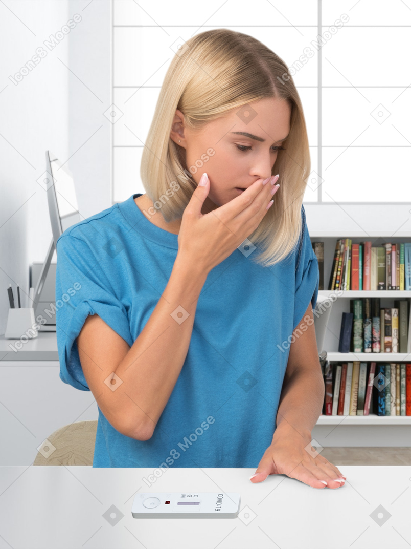 A worried young woman sitting at the table with a covid-19 test on it