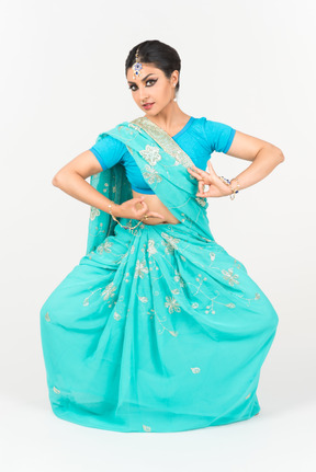 Joven mujer india en sari azul de pie en posición de baile