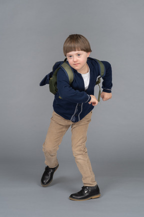 Portrait of a schoolboy walking with his arms raised