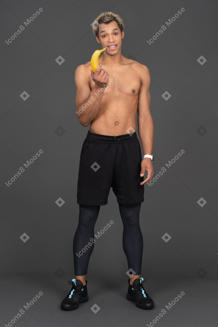 Vista frontal de un joven afro sosteniendo el plátano