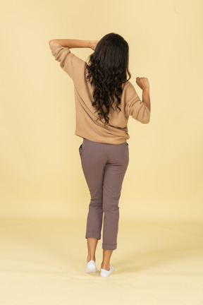 Vista posterior de una mujer joven de piel oscura somnolienta estirando su espalda