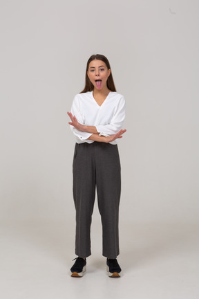 Vista frontale di una giovane donna in abiti da ufficio incrociando le mani e mostrando la lingua
