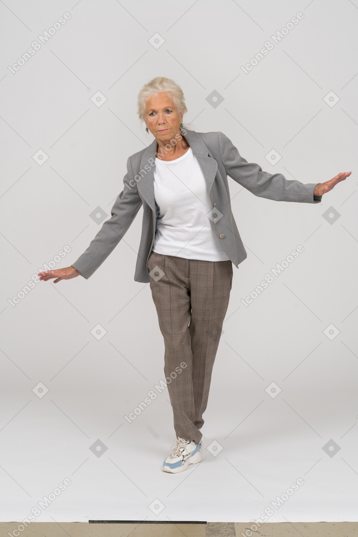 Vorderansicht einer alten dame im anzug, die mit ausgestreckten armen steht