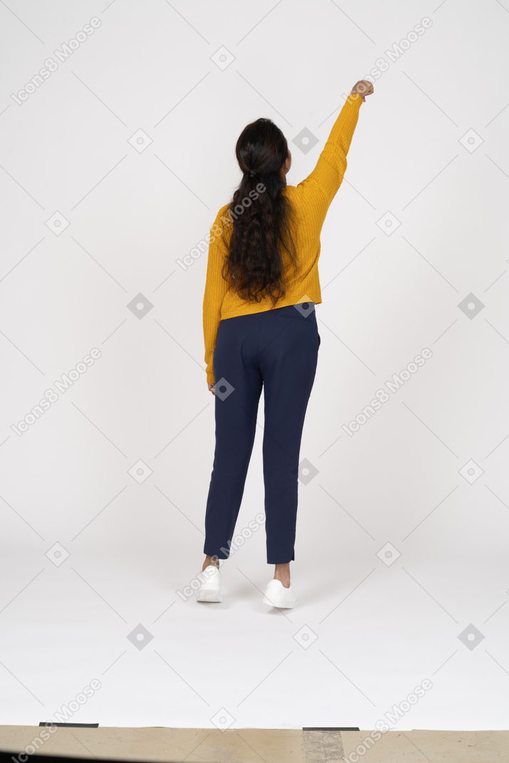 腕を上げて立っているカジュアルな服装の女の子の背面図