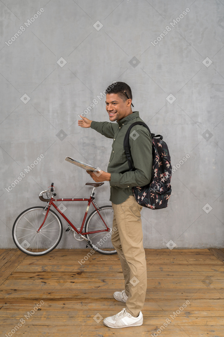 Side view of a man with a backpak and a map showing directions and smiling