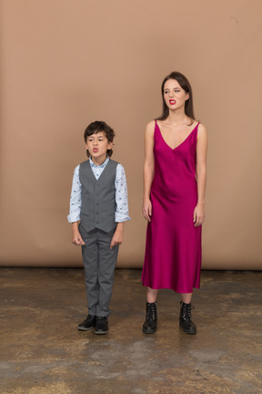 Front view of a grinning boy and woman in red dress