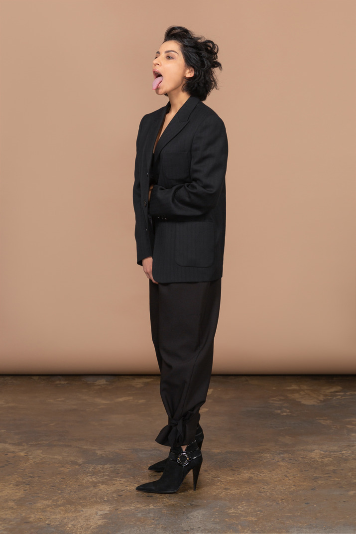 Three-quarter view of a businesswoman in a black suit leaning forward and showing tongue