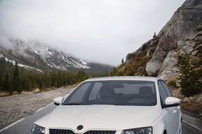 A white car parked on the side of a mountain road