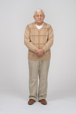 Vista frontal de un anciano con ropa informal de pie con las manos cruzadas