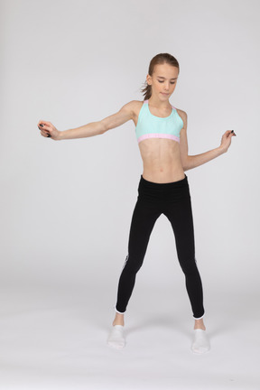 十几岁的女孩在跳舞时伸出手的运动服的前视图
