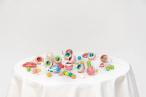 Candy eyeballs and another candies on white tablecloth