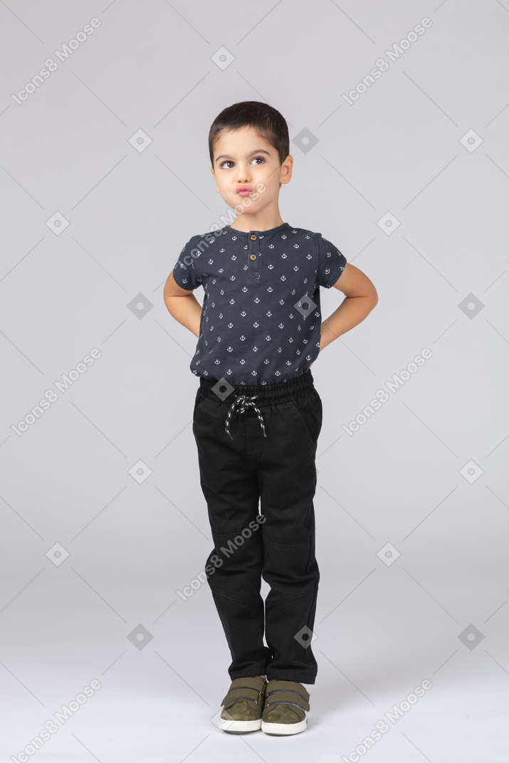 一个穿着休闲服的可爱男孩的前视图，双手在背后摆姿势