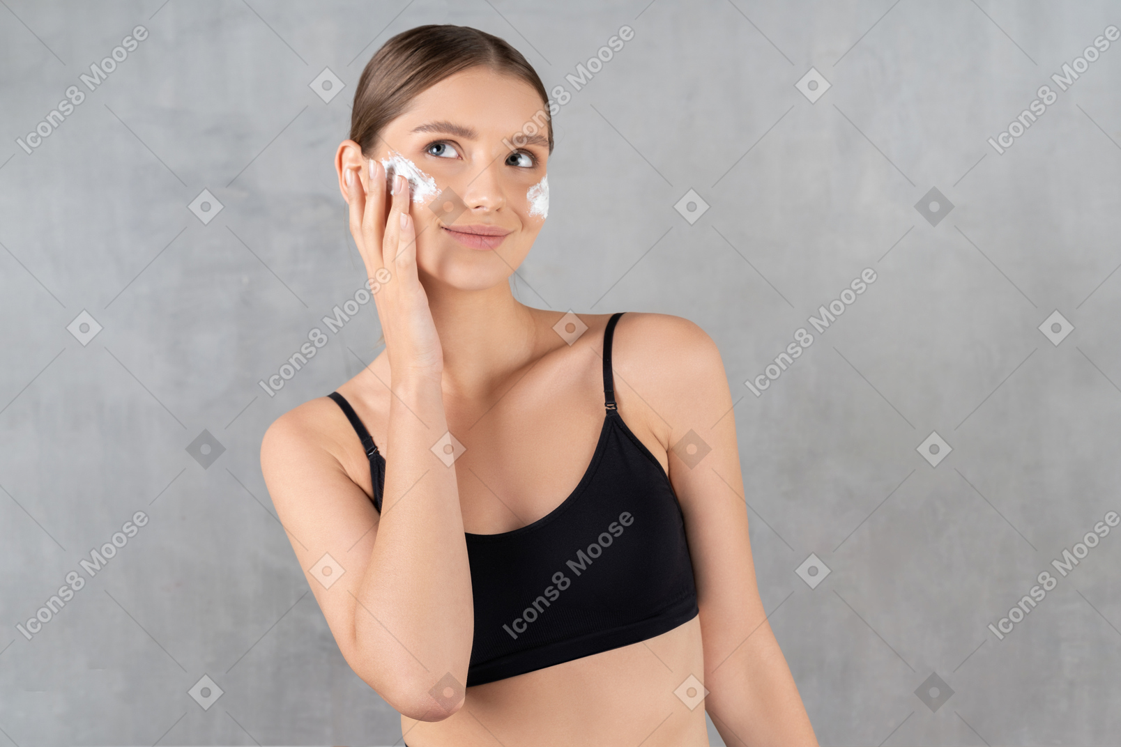 Smiling woman applying cream on her cheeks