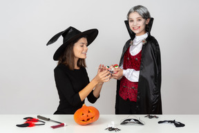 Ragazzo in costume da vampiro che mostra un mucchio di caramelle alla mamma