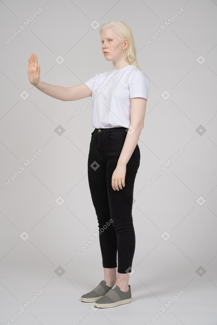Vista de tres cuartos de una niña que muestra el signo de la mano de parada