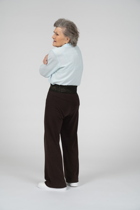 Retrovisione della donna anziana che guarda sopra la sua spalla