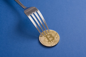 Bitcoin e forchetta su sfondo blu