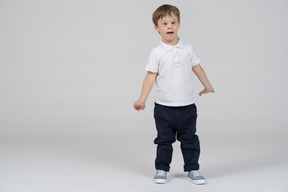 Surprised little boy standing with arms at sides