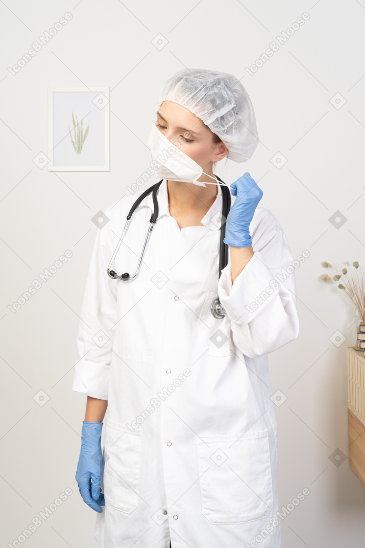 Front view of a young female doctor taking mask off