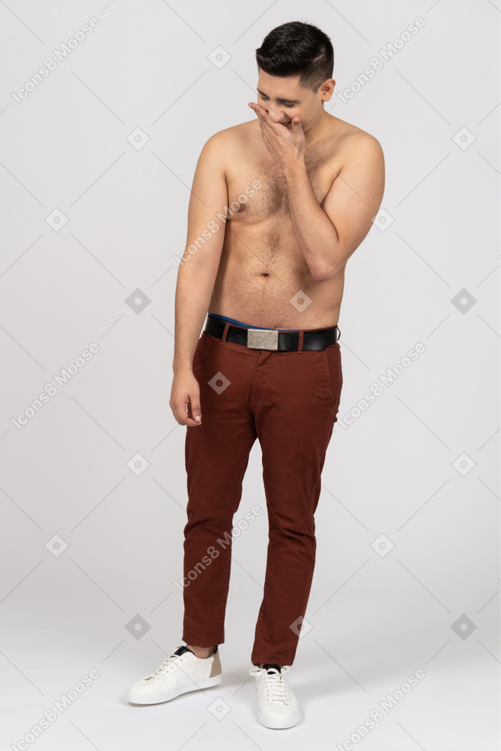 Vista frontal de um homem latino sem camisa, cobrindo a boca timidamente