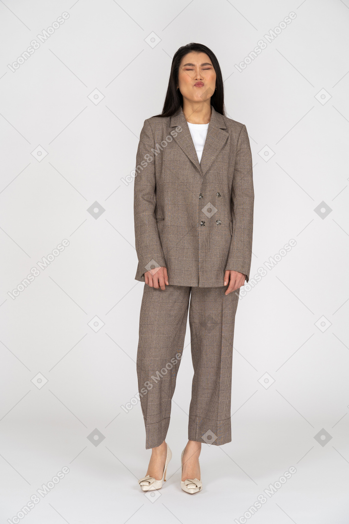 Front view of a pouting young lady in brown business suit closing her eyes