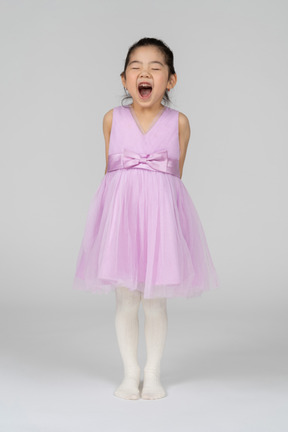 一个穿着芭蕾舞短裙打呵欠的小女孩的正面图