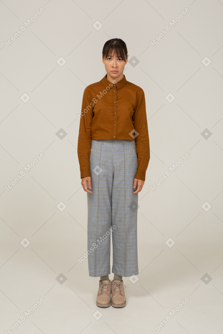 Front view of an upset young asian female in breeches and blouse standing still
