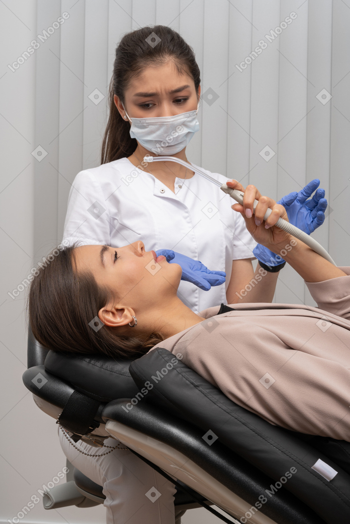 Picture of a curious female patient with perplexed dentist on the background