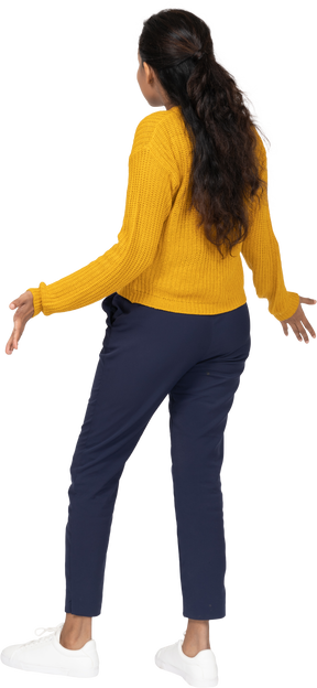 Rear view of a girl in casual clothes standing with outstretched arms