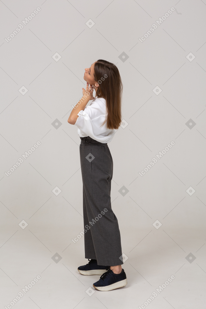 Vista laterale di una giovane donna in abiti da ufficio che le tocca il viso