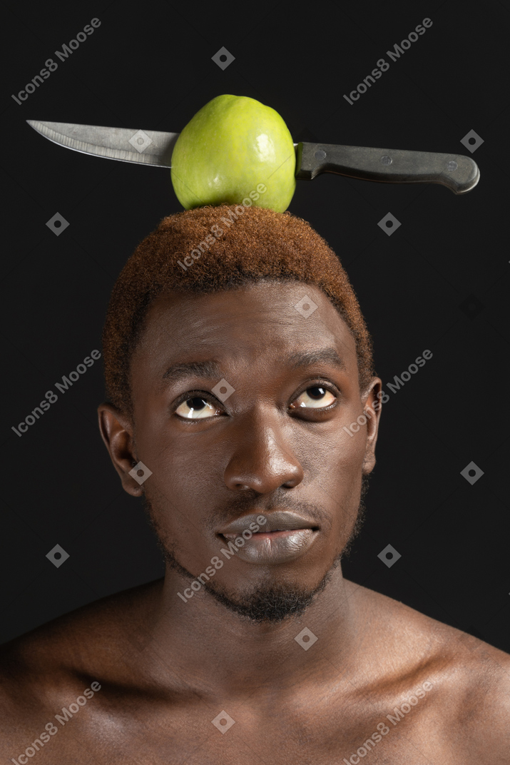 Retrato de um homem africano com uma maçã perfurada com uma faca na cabeça