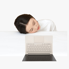 Woman laying her head on a desk next to laptop