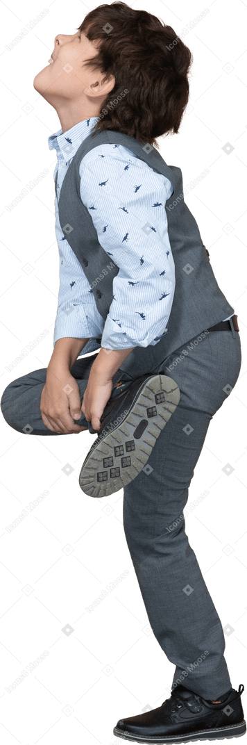 Vista lateral de um menino de terno cinza, sofrendo de dor na perna