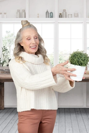 A woman holding a potted plant in a kitchen