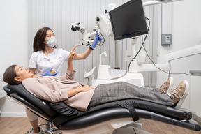 Full-length of a female dentist consulting her female patient while both pointing to a screen