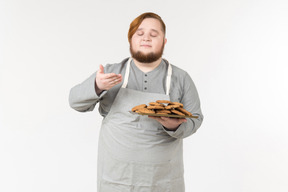 Um homem gordo cheirando biscoitos recém-assados