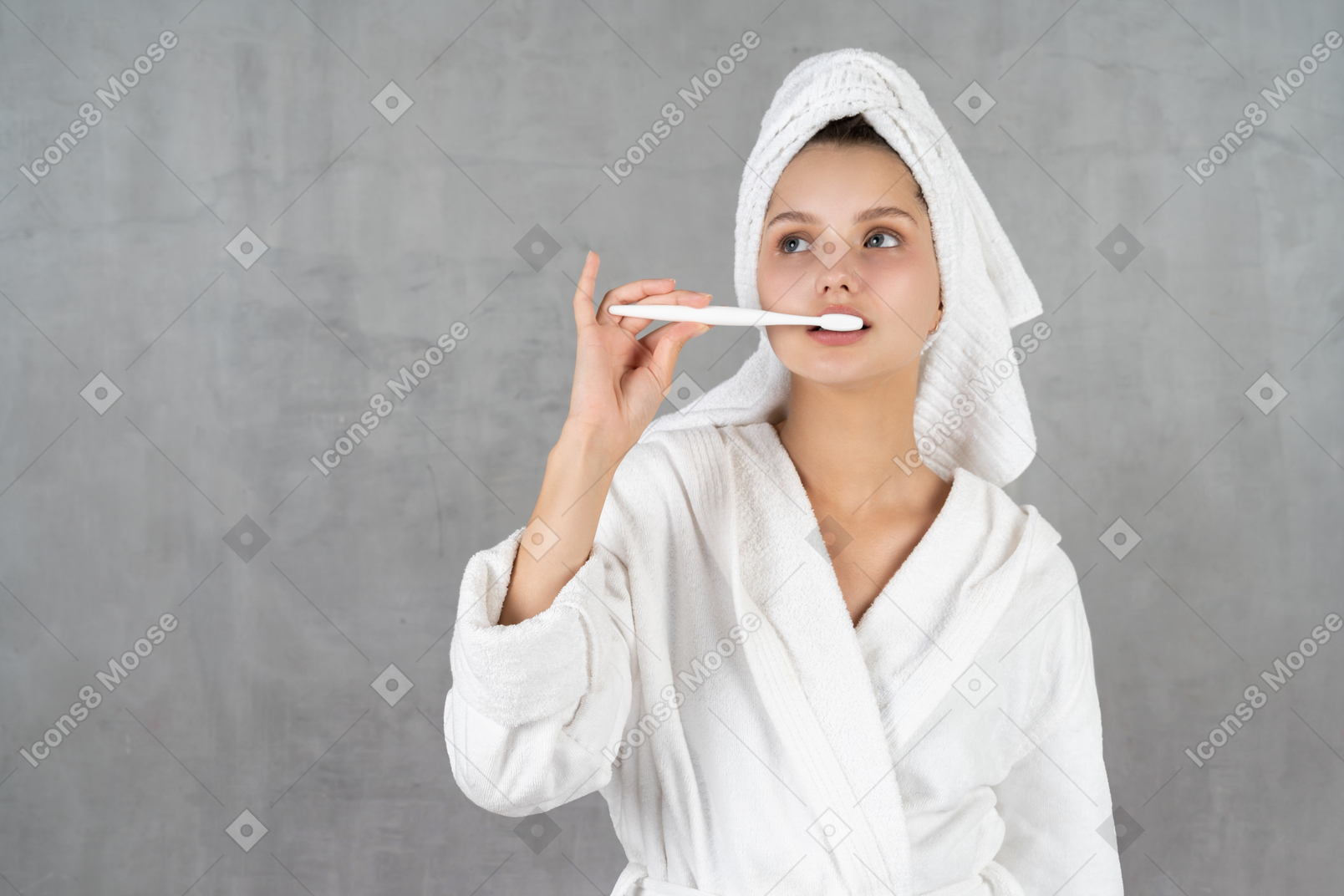 Woman in bathrobe brushing her teeth