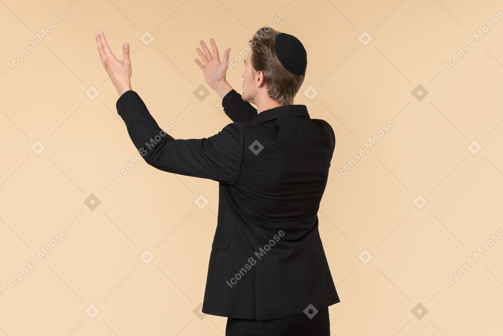 Young man in a black suit and a kippah praying