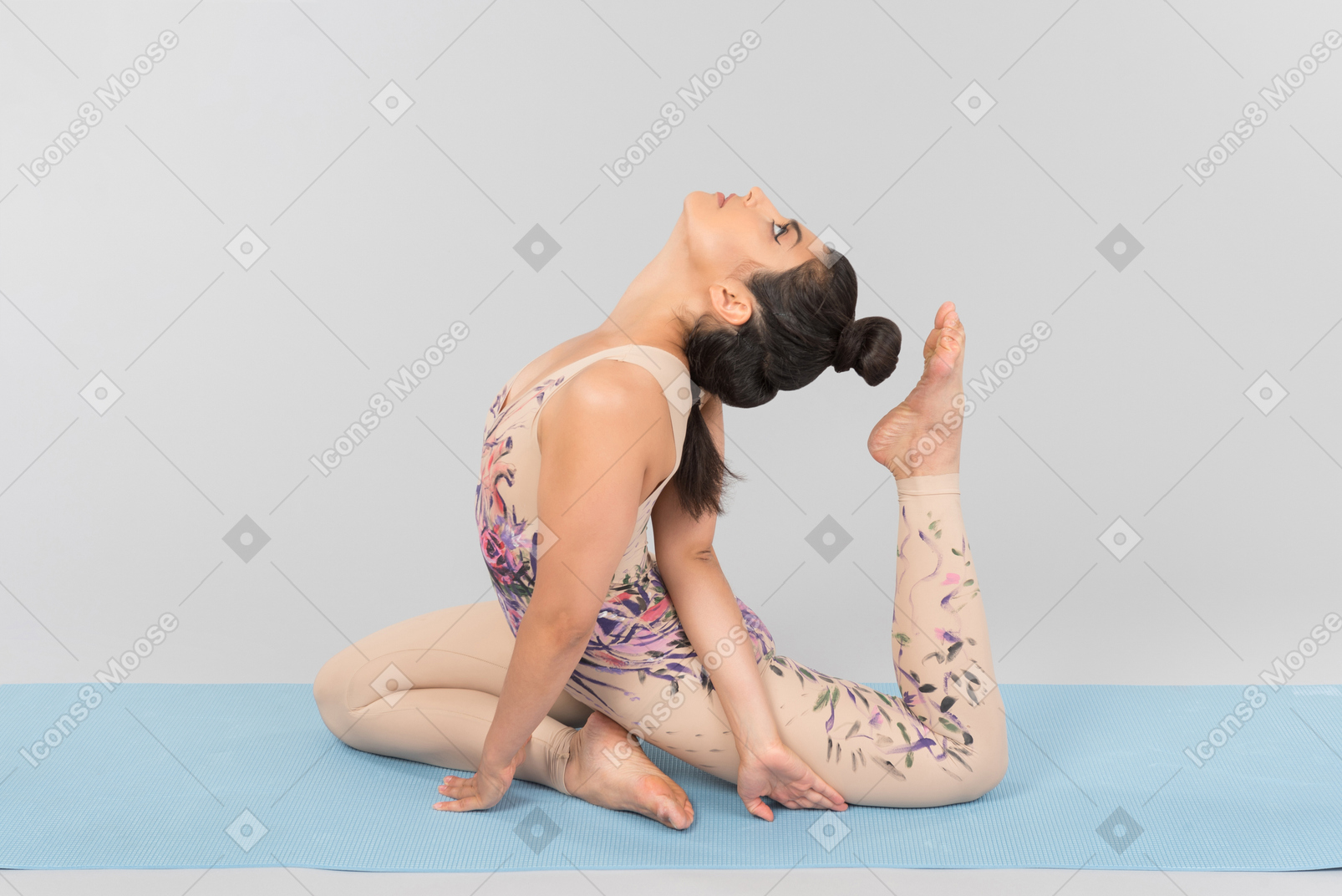 Junge indische turnerin, die auf yogamatte liegt und fast ihren kopf mit einem zeh berührt