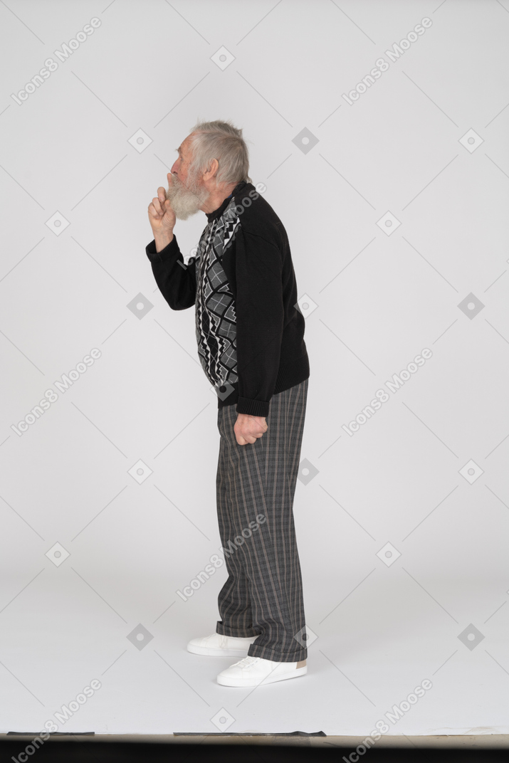 Side view of old man with finger on lips