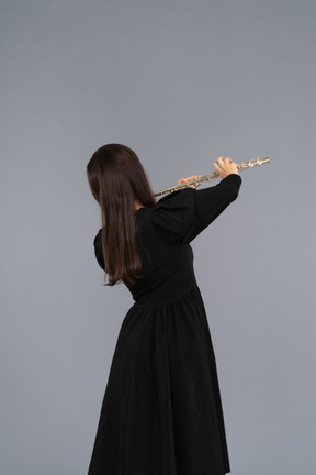 Black view of a young lady in black dress playing the flute