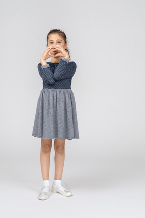 Vista frontal de una niña haciendo un círculo con las manos y tocando los codos
