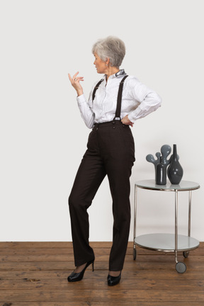 Vista frontal de uma senhora gesticulando pensativa em roupas de escritório