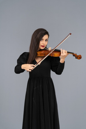 Close-up de uma jovem de vestido preto tocando violino