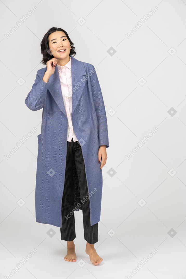 Smiling woman in coat touching neck