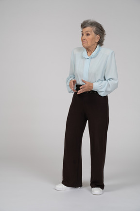 Vista frontal de una anciana encogiéndose de hombros
