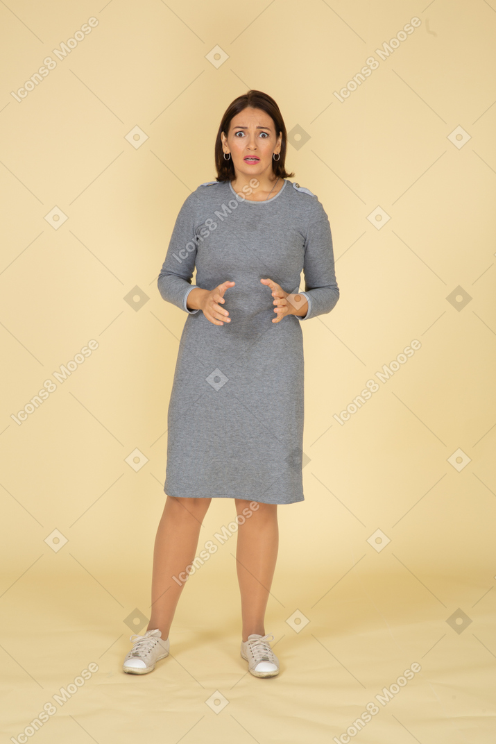 Vista frontale di una donna spaventata in abito grigio