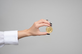 Mano femenina sosteniendo un bitcoin dorado