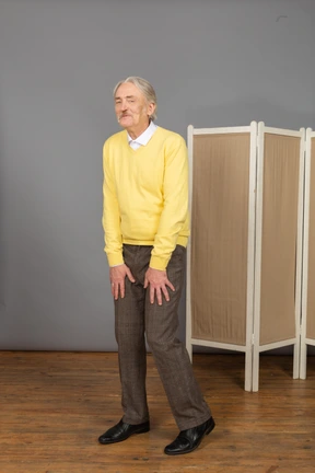 Three-quarter view of a grimacing old man putting hands in legs